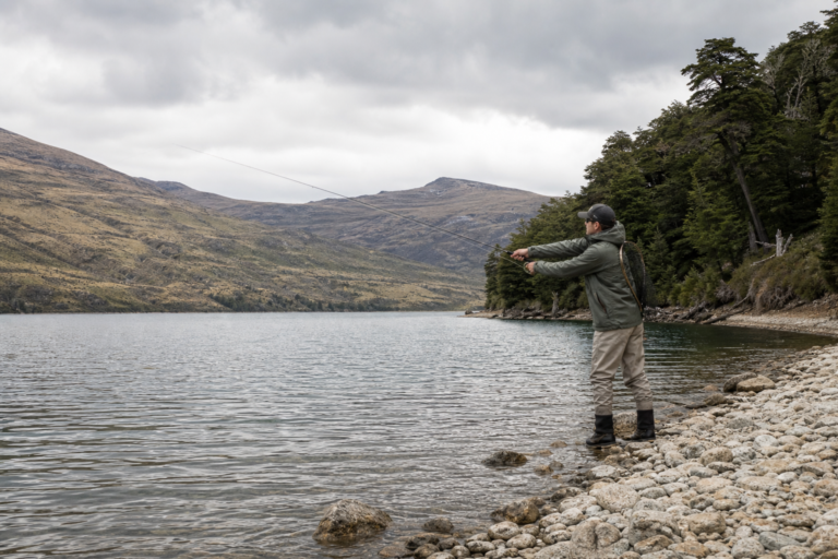 Trout angler casting from the shore of a wind-ruffled New Zealand lake